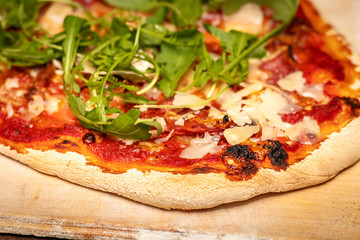 Pizza mit Parmesan und Ruccola auf Holzbrett, frisch aus dem Backofen