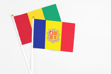 Andorra and Guinea stick flags on white background. High quality fabric, miniature national flag. Peaceful global concept.White floor for copy space.