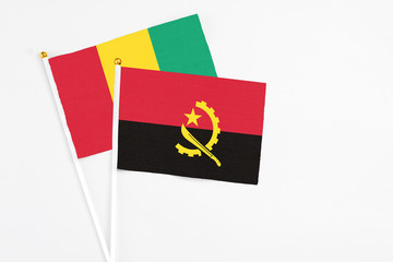 Angola and Guinea stick flags on white background. High quality fabric, miniature national flag. Peaceful global concept.White floor for copy space.