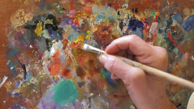 mano mezclando colores en paleta de pintor