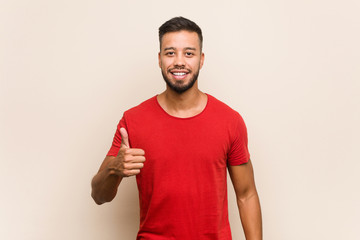 Young south-asian man smiling and raising thumb up