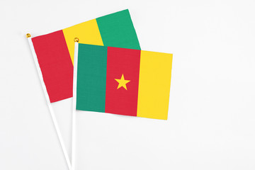 Cameroon and Guinea stick flags on white background. High quality fabric, miniature national flag. Peaceful global concept.White floor for copy space.
