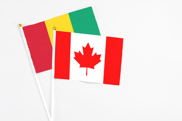 Canada and Guinea stick flags on white background. High quality fabric, miniature national flag. Peaceful global concept.White floor for copy space.