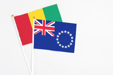 Fototapeta premium Cook Islands and Guinea stick flags on white background. High quality fabric, miniature national flag. Peaceful global concept.White floor for copy space.