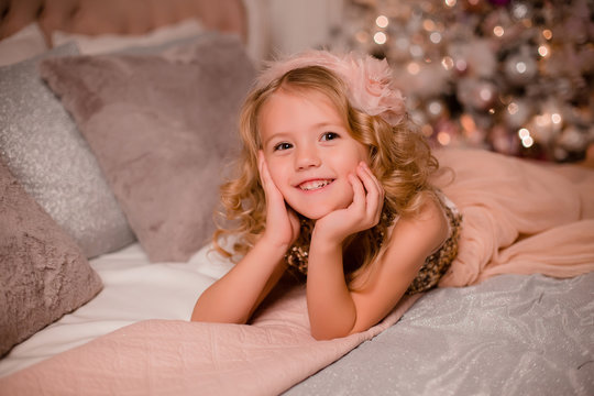 little blonde girl in bed next to Christmas tree. christmas eve