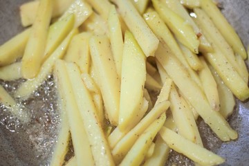 Potatoes are fried in oil. Sliced potatoes in a pan.
