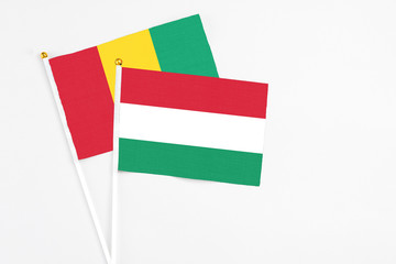 Hungary and Guinea stick flags on white background. High quality fabric, miniature national flag. Peaceful global concept.White floor for copy space.