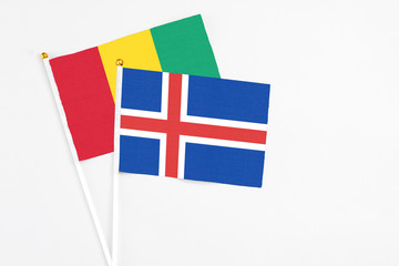 Obraz premium Iceland and Guinea stick flags on white background. High quality fabric, miniature national flag. Peaceful global concept.White floor for copy space.