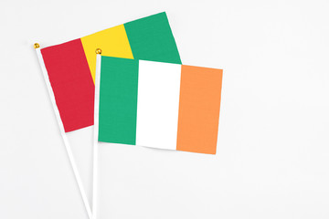 Ireland and Guinea stick flags on white background. High quality fabric, miniature national flag. Peaceful global concept.White floor for copy space.