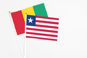 Liberia and Guinea stick flags on white background. High quality fabric, miniature national flag. Peaceful global concept.White floor for copy space.