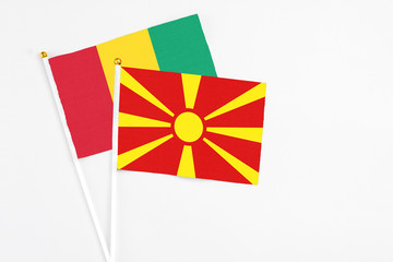 Macedonia and Guinea stick flags on white background. High quality fabric, miniature national flag. Peaceful global concept.White floor for copy space.