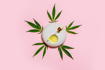 CBD cannabis oil with hemp leaves on pink background.
