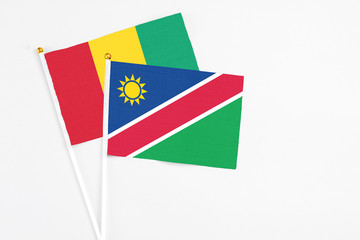 Namibia and Guinea stick flags on white background. High quality fabric, miniature national flag. Peaceful global concept.White floor for copy space.