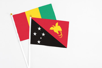 Papua New Guinea and Guinea stick flags on white background. High quality fabric, miniature national flag. Peaceful global concept.White floor for copy space.