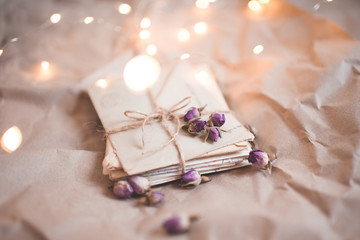 Stack of old vintage letters with flowers closeup over lights at background. Valentines Day.