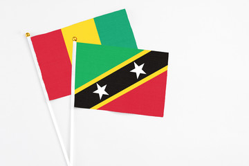 Saint Kitts And Nevis and Guinea stick flags on white background. High quality fabric, miniature national flag. Peaceful global concept.White floor for copy space.