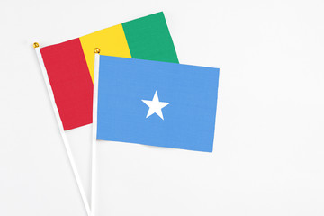 Somalia and Guinea stick flags on white background. High quality fabric, miniature national flag. Peaceful global concept.White floor for copy space.