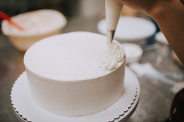 White cake decoration, close-up. Pastry chef decorating cake.