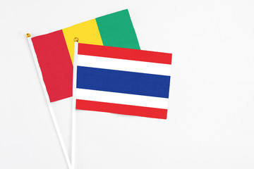 Thailand and Guinea stick flags on white background. High quality fabric, miniature national flag. Peaceful global concept.White floor for copy space.