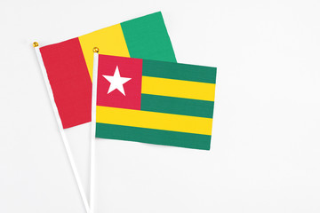 Togo and Guinea stick flags on white background. High quality fabric, miniature national flag. Peaceful global concept.White floor for copy space.