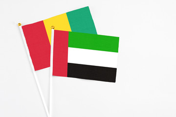 United Arab Emirates and Guinea stick flags on white background. High quality fabric, miniature national flag. Peaceful global concept.White floor for copy space.