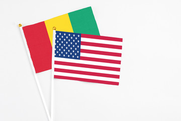 United States and Guinea stick flags on white background. High quality fabric, miniature national flag. Peaceful global concept.White floor for copy space.