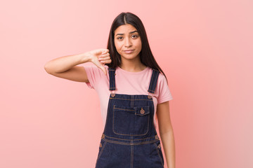 Young pretty arab woman wearing a jeans dungaree showing a dislike gesture, thumbs down....