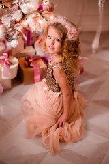 Fototapeta na wymiar little blonde girl decorates Christmas tree in beautiful interior