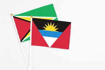 Antigua and Barbuda and Guyana stick flags on white background. High quality fabric, miniature national flag. Peaceful global concept.White floor for copy space.