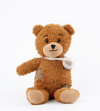 brown teddy bear with rewound white bandage paw on a white background