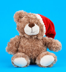 little cute brown teddy bear with in a red Christmas hat