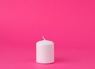 Obraz na płótnie Canvas new white wax candle on a pink background