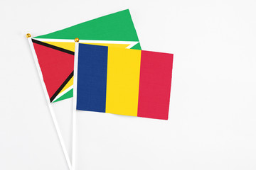 Chad and Guyana stick flags on white background. High quality fabric, miniature national flag. Peaceful global concept.White floor for copy space.