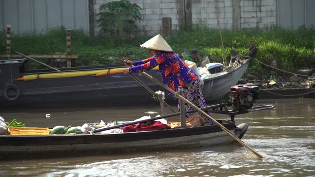 Female using oars to row market boat Vietnam 