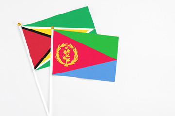 Eritrea and Guyana stick flags on white background. High quality fabric, miniature national flag. Peaceful global concept.White floor for copy space.