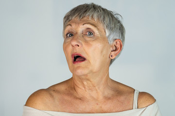 older woman with gray hair and blue eyes with surprise expression in White background