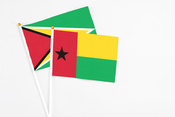 Guinea Bissau and Guyana stick flags on white background. High quality fabric, miniature national flag. Peaceful global concept.White floor for copy space.