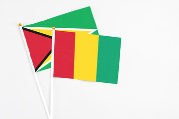 Guinea and Guyana stick flags on white background. High quality fabric, miniature national flag. Peaceful global concept.White floor for copy space.