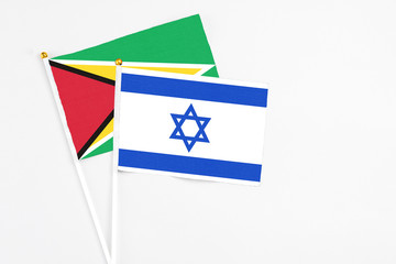 Israel and Guyana stick flags on white background. High quality fabric, miniature national flag. Peaceful global concept.White floor for copy space.