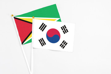 South Korea and Guyana stick flags on white background. High quality fabric, miniature national flag. Peaceful global concept.White floor for copy space.