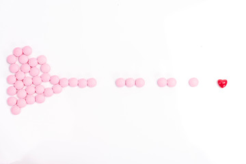 Pink pills on a white background with a red heart. Heart pills