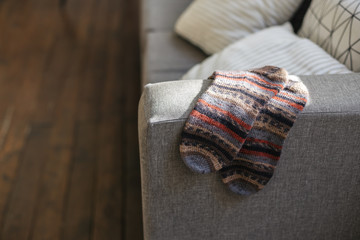 Pair of hand knitted socks on the sofa in modern interior.