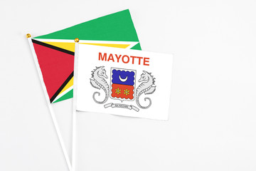 Mayotte and Guyana stick flags on white background. High quality fabric, miniature national flag. Peaceful global concept.White floor for copy space.