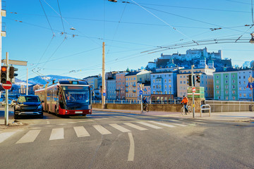 Cityscape with car and bus on street road at Salzburg Castle in Austria. Traffic in Mozart city in Europe at winter. Panorama and landmark during Christmas. View of old Austrian town of Salzburgerland - obrazy, fototapety, plakaty