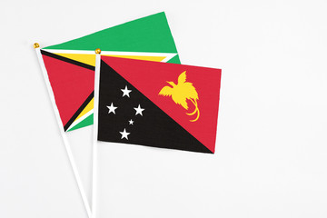 Papua New Guinea and Guyana stick flags on white background. High quality fabric, miniature national flag. Peaceful global concept.White floor for copy space.