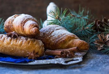 Christmas and New Year background with continental breakfast - with cinnamon orange and croissant. Decorations - snowflake , pine cones.