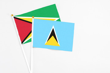 Saint Lucia and Guyana stick flags on white background. High quality fabric, miniature national flag. Peaceful global concept.White floor for copy space.