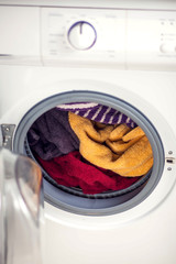 Loading clothes in washing machine. Housework and laundry concept