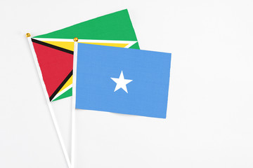 Somalia and Guyana stick flags on white background. High quality fabric, miniature national flag. Peaceful global concept.White floor for copy space.