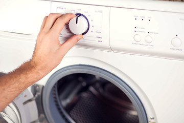Man switches on the washing machine and choses washing mode